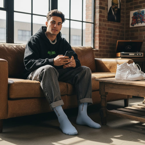 Cook Gods light blue crew socks with gold writing on the cuff, worn by a man sitting on a couch.