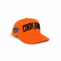 Cook Gods orange snapback hat with black embroidered "COOK GODS" logo on front and "COOK UPPS" on side.